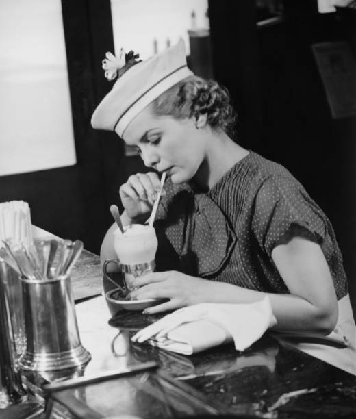 giovane donna in un cappello fantasia bere gelato soda (b & w - soda fountain foto e immagini stock