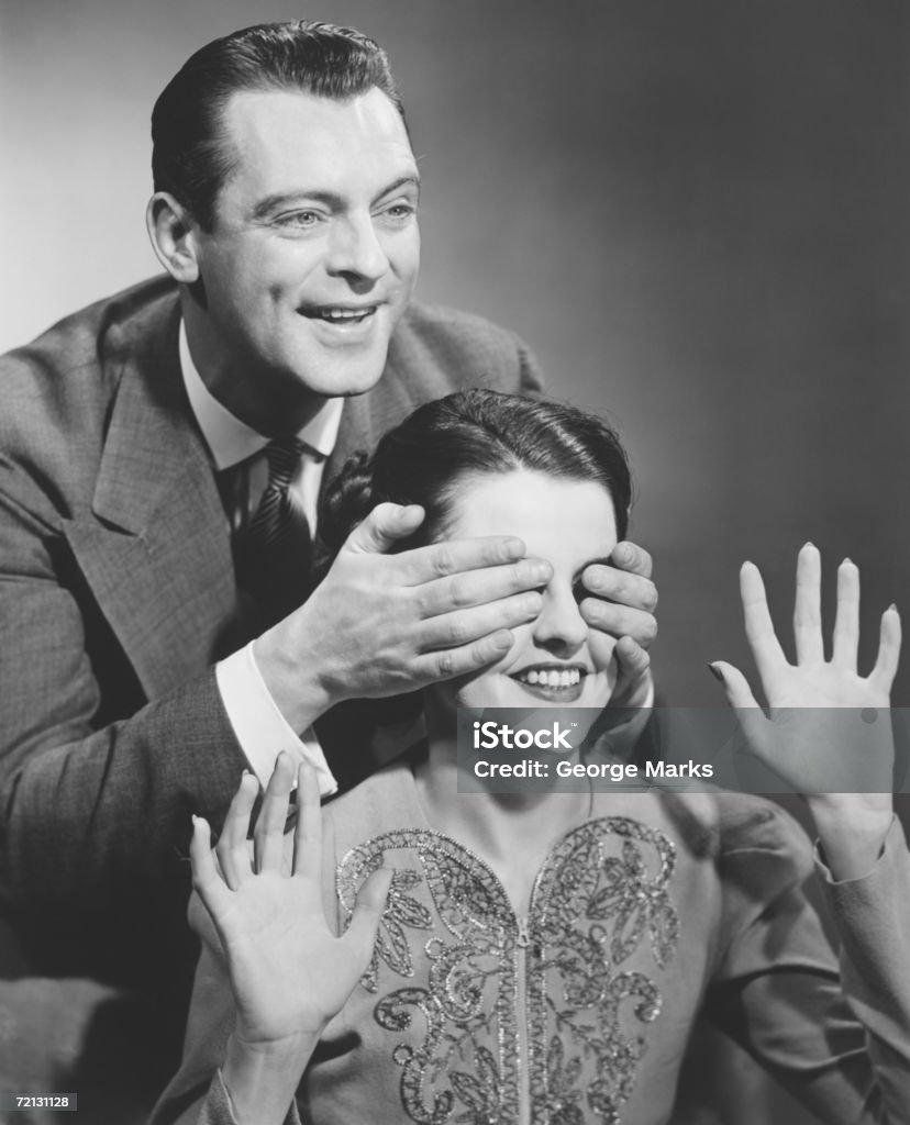 HOMME DEBOUT derrière la femme couvrant ses yeux (B & W - Photo de 1950-1959 libre de droits