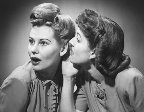 Two women gossiping in studio (B&W)  language photos stock pictures, royalty-free photos & images