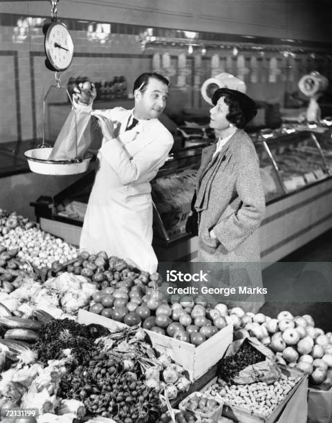 Store Clerk Weighing Tomatoes For Client Stock Photo - Download Image Now - Old-fashioned, Black And White, Store