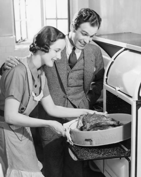 casal na cozinha, mulher tirar do forno assado (b & m - estereótipo de dona de casa imagens e fotografias de stock