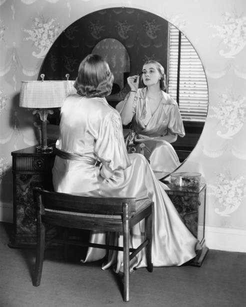mulher aplicando compõem em frente de vaidade tabela (b & m - woman in mirror backview imagens e fotografias de stock