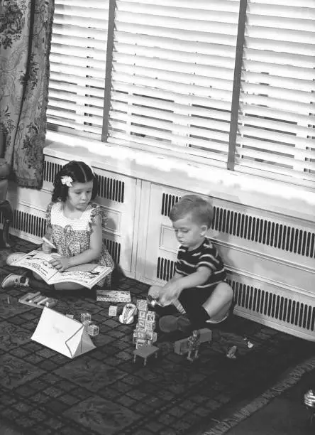 Photo of Brother (4-5) and sister (6-7) playing on floor in family room, (B&W)