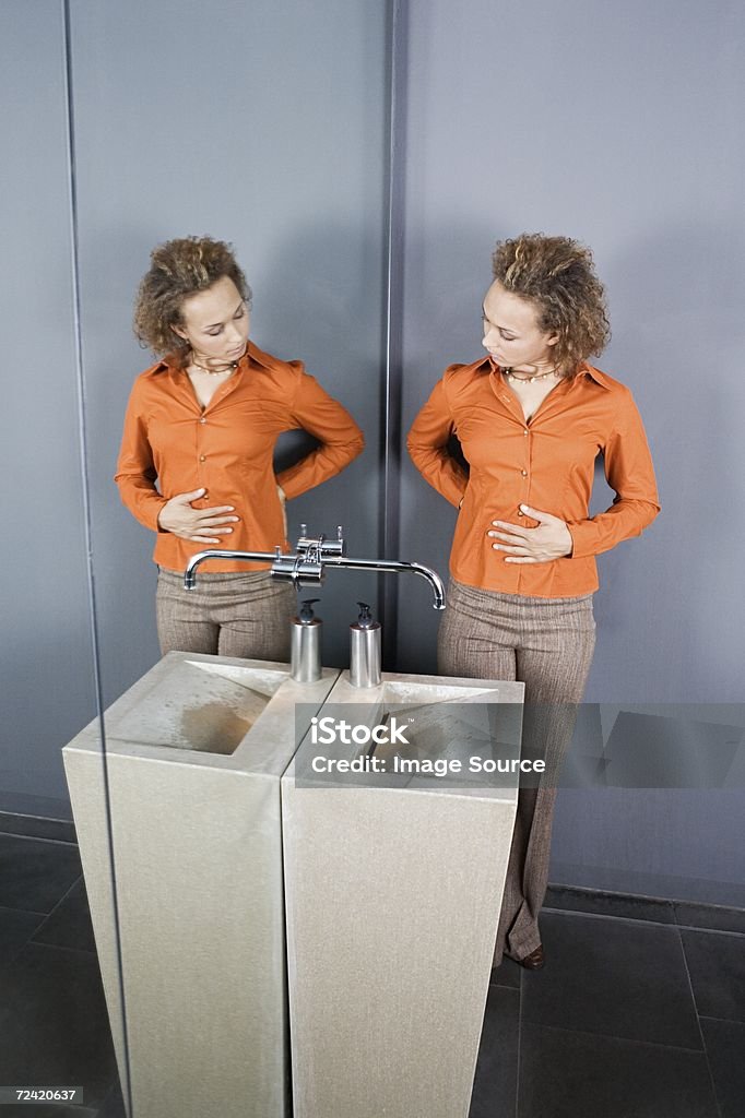 Donna guardando se stessa in specchio - Foto stock royalty-free di Addome