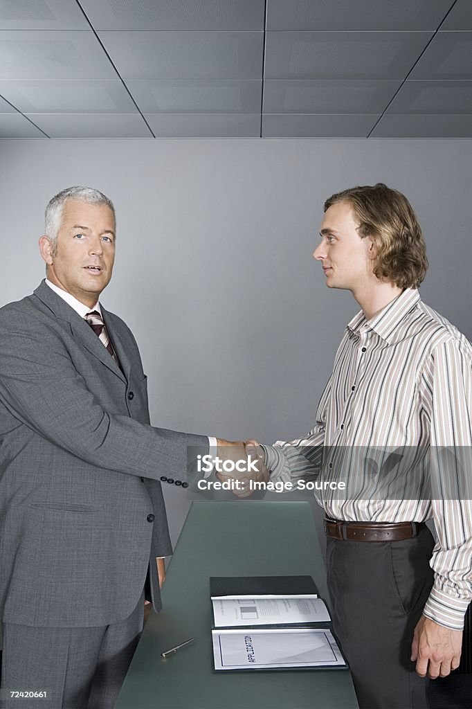 Empresario agitando las manos con hombre joven - Foto de stock de Acontecimiento libre de derechos