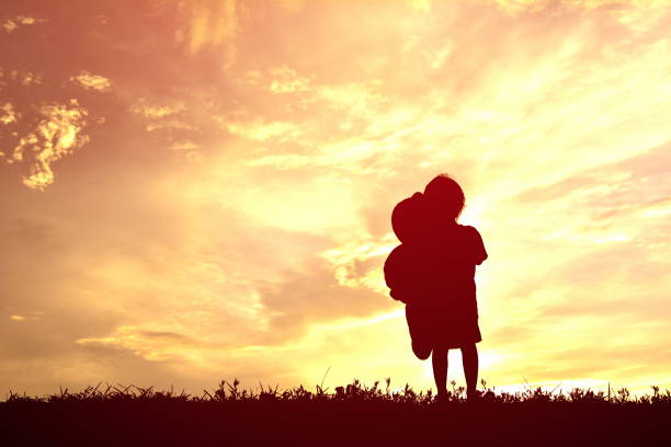 istock Silhouette Girl Holding Teddy Bear On Field Against Sky During Sunset 726848719