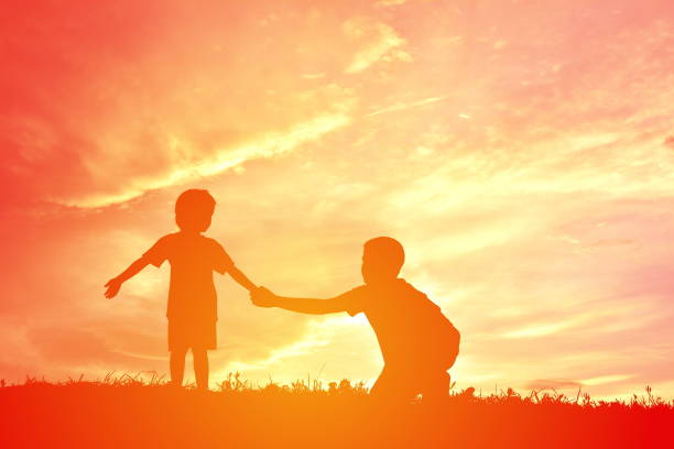 istock Silhouette Siblings Holding Hands On Field Against Sky During Sunset 726867315
