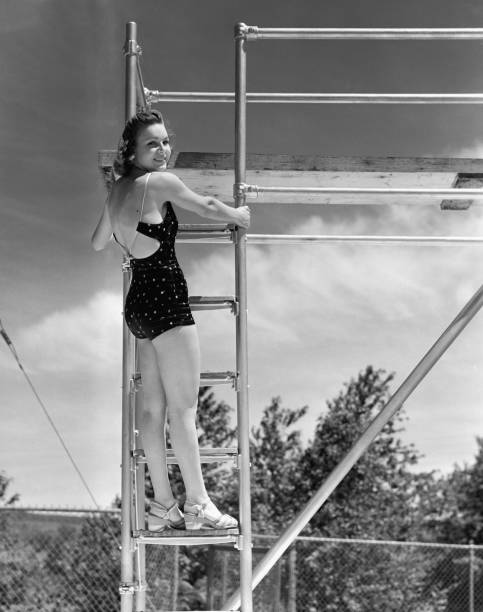 Woman standing on ladder at springboard, (B&W)  one piece swimsuit photos stock pictures, royalty-free photos & images