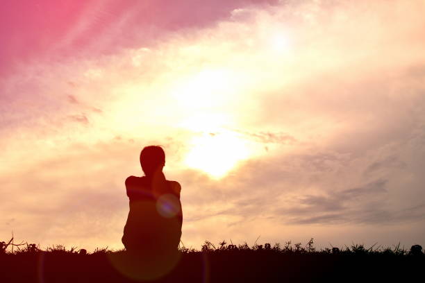istock Silhouette Woman Sitting On Field Against Sky During Sunset 727143909