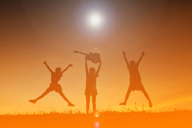 istock Silhouette Siblings With Guitar Jumping On Field Against Sky During Sunset 727144465