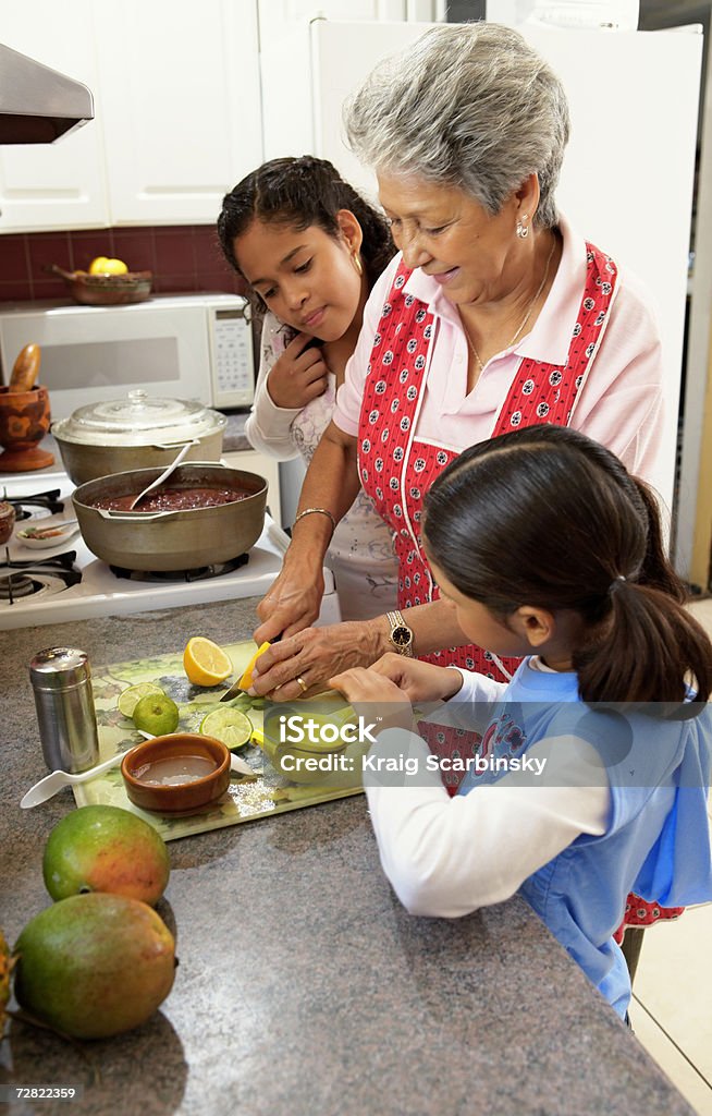Netas (de 6 a 12) assistir a avó na cozinha - Foto de stock de Família royalty-free