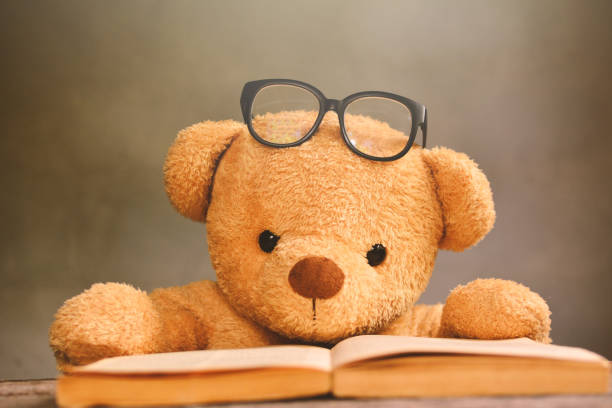 istock Teddy Bear With Eyeglasses By Book On Table Against Wall 728880189