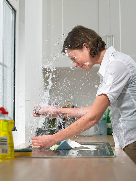 donna nel lavello in cucina domestica vengono inondate da - lavandino rotto foto e immagini stock