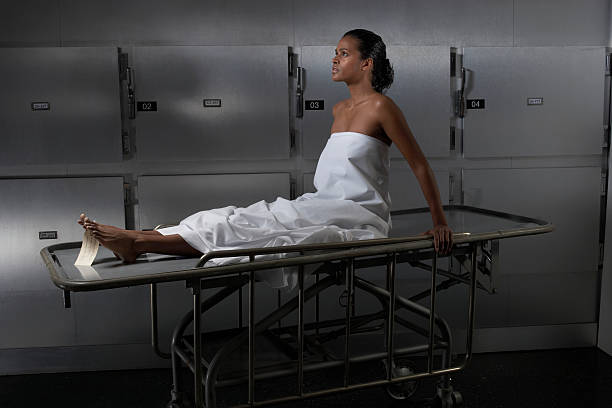 Woman sitting on hospital trolley, side view  morgue stock pictures, royalty-free photos & images