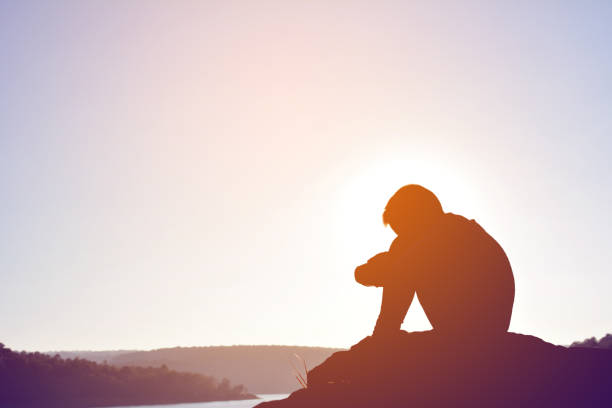 istock Side View Of Silhouette Boy Sitting Against Sky During Sunset 730192585