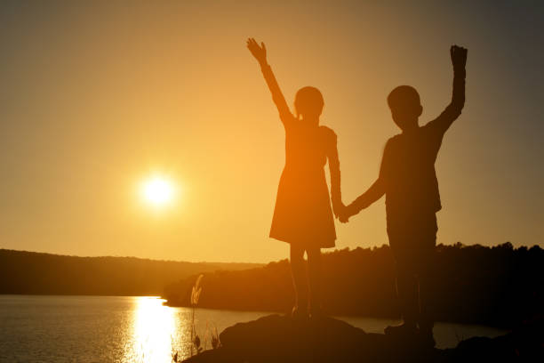 istock Silhouette Friends Holding Hands While Standing Against Sky During Sunset 730193285