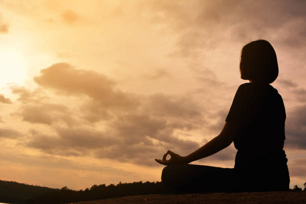 istock Low Angle View Of Woman Meditating Against Cloudy Sky During Sunset 730195595