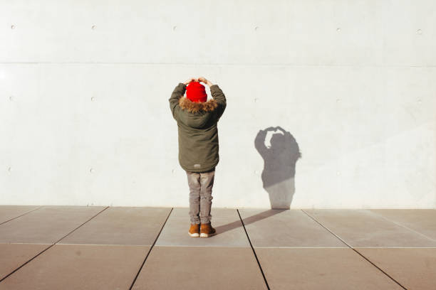 Vista trasera de un niño con sombra en la pared - foto de stock