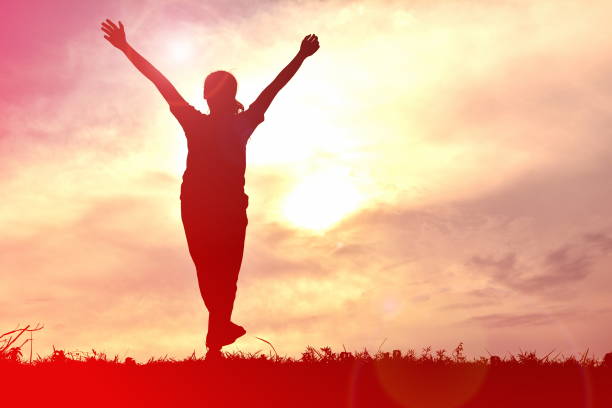 istock Silhouette Woman Standing With Arms Raised On Field During Sunset 730288413