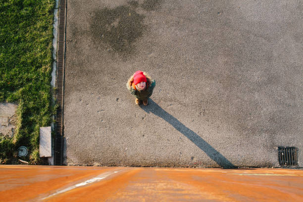 High Angle View Of Girl Standing On Street By Orange Wall - fotografia de stock