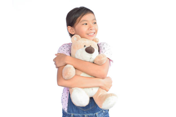 istock Girl Embracing Teddy Bear While Standing Against White Background 731854451