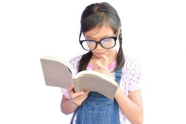 istock Girl In Eyeglasses Reading Book While Standing Against White Background 731855565