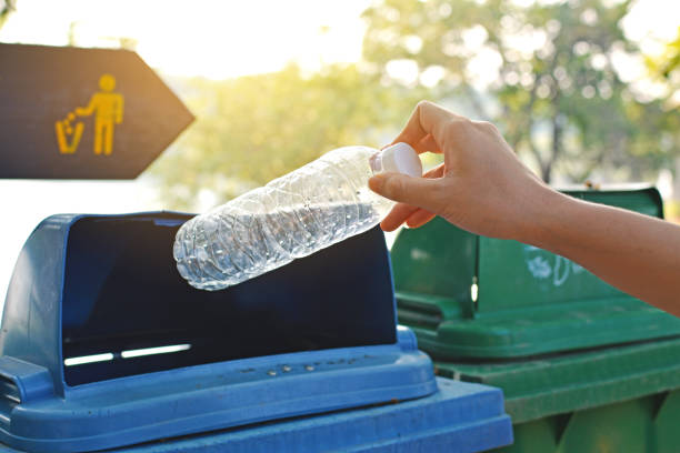 istock Close-Up Of Hand Throwing Bottle Into Trash Can 731861875