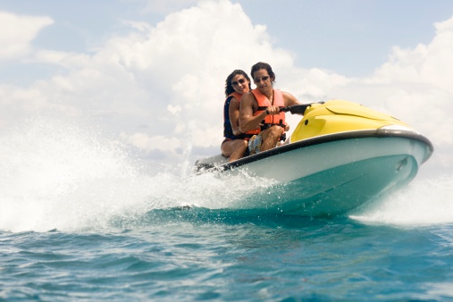 Young couple jet skiing on the open sea. They are smiling and enjoying summer sport on water.