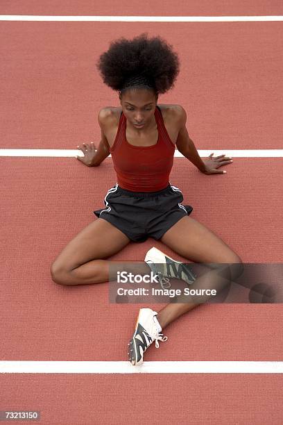 Velocista Feminino Alongamentos Em Uma Pista De Corrida - Fotografias de stock e mais imagens de Adulto