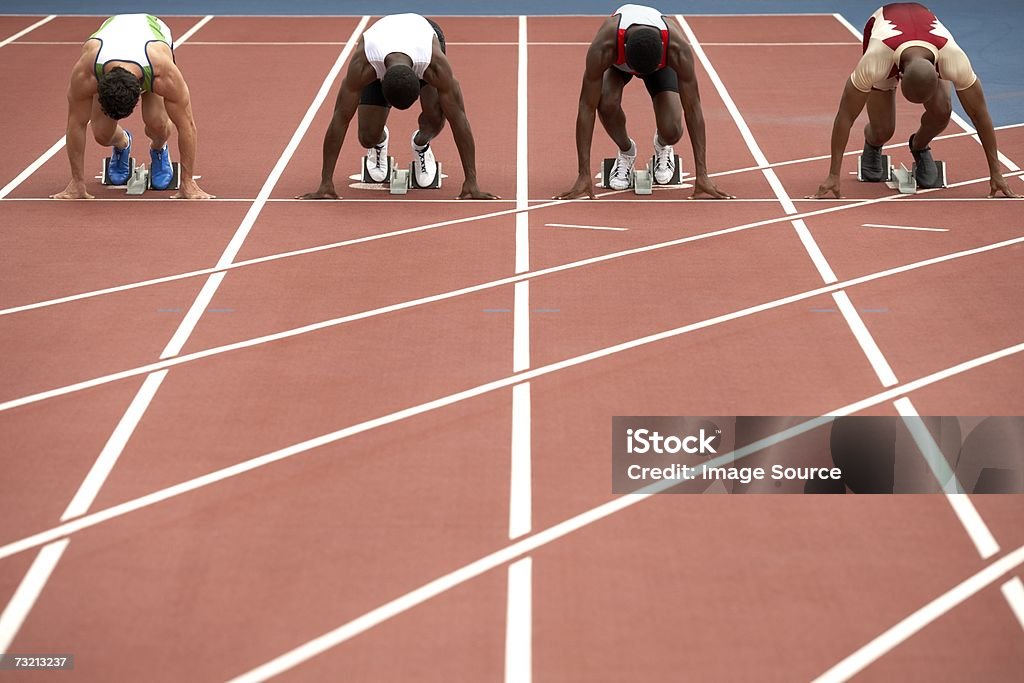 Cuatro sprinters en una pista de carreras - Foto de stock de Adulto libre de derechos