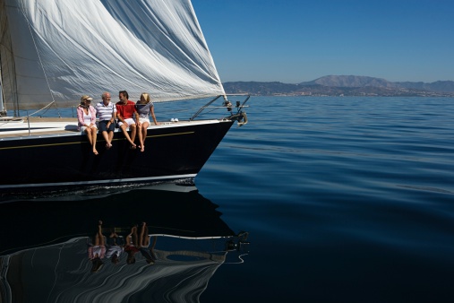 Happy friends diving from sailing boat into the sea - Soft focus on girls faces