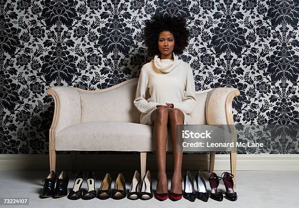 Woman Sitting On Sofa With Pair Of Shoes On Floor Portrait Stock Photo - Download Image Now