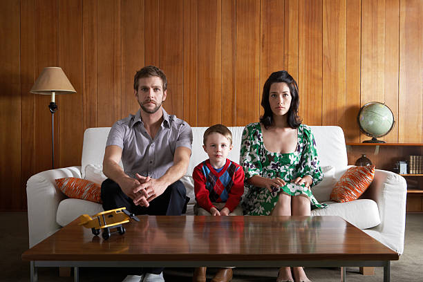 parents et fils (de 3 à 5) assis sur le canapé dans la salle de séjour - famille avec un enfant photos et images de collection