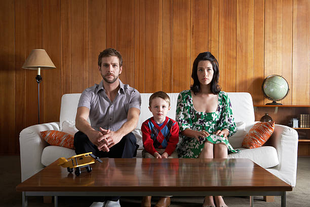 genitori e figlio (3-5) seduta sul divano in salotto - family father child mother foto e immagini stock