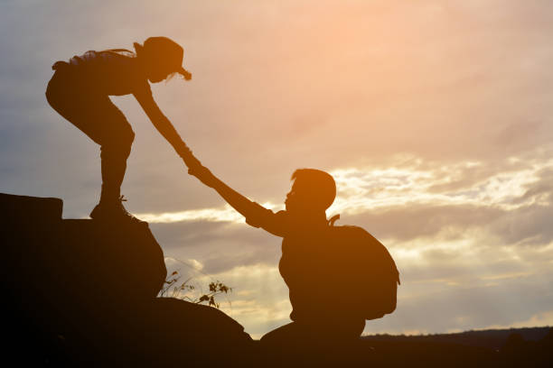istock Silhouette Boy Assisting Girl While Hiking Against Sky During Sunset 733477629