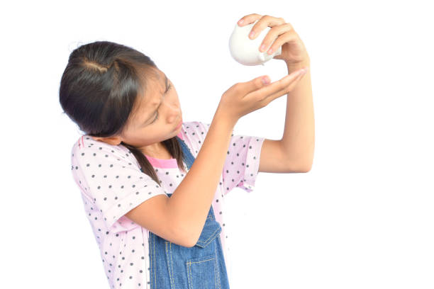 istock Girl Looking At Piggy Bank While Standing Against White Background 733520347
