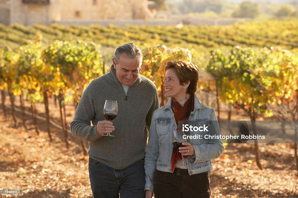 Mature couple standing in vineyard, holding glasses of wine, smiling  Vineyard Stock Photo