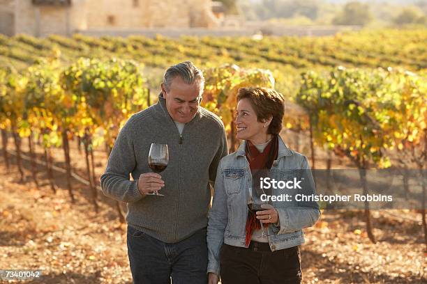 Mature Couple Standing In Vineyard Holding Glasses Of Wine Smiling Stock Photo - Download Image Now