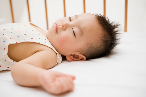Cute five month old baby sleeping in comfortable bed. Concept of the family and parenting.