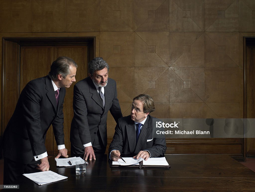 Uomini maturi Guardando oltre documenti alla fine della tabella - Foto stock royalty-free di Sala conferenze