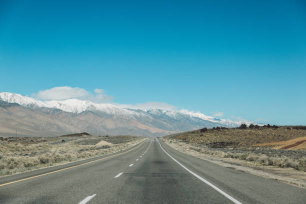 istock Empty Road Amidst Landscape Against Clear Blue Sky 736025481