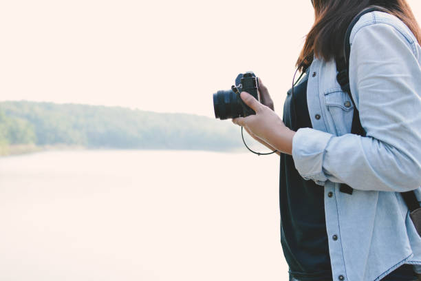 istock Midsection Of Woman Holding Camera While Standing By Sea Against Clear Sky 736516501