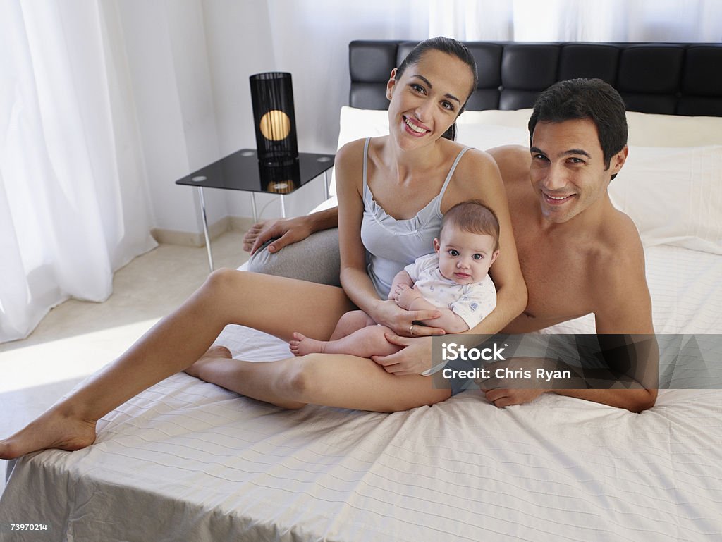 Coppia posa su un letto con figlia - Foto stock royalty-free di 2-5 Mesi