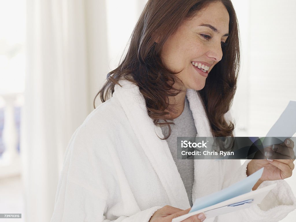 Donna in accappatoio leggere una lettera - Foto stock royalty-free di Leggere