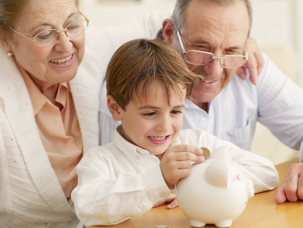 Grandparents teaching grandson to save money in a piggy bank  age contrast stock pictures, royalty-free photos & images