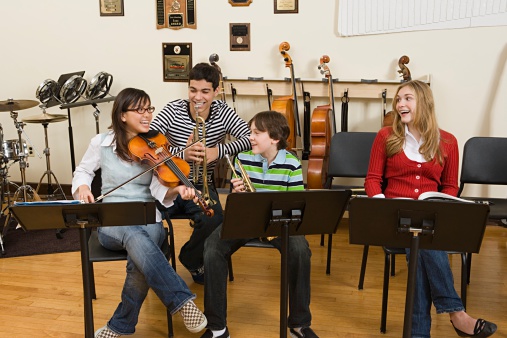 Young adult caucasian man student learning to play violin with help of his professor woman female mentor teaching him how to improve skill at home explaining lesson real people private class concept