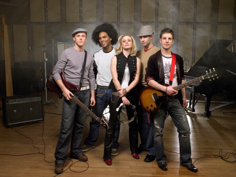 photo of multi ethnic music band in studio.Musicians and woman soloist posing over white background.