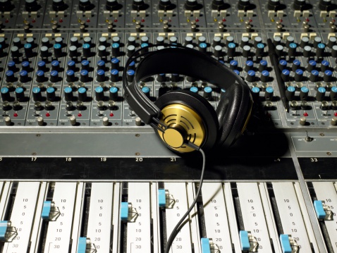 African producer in headphones using music keyboard to write a new song in the recording studio