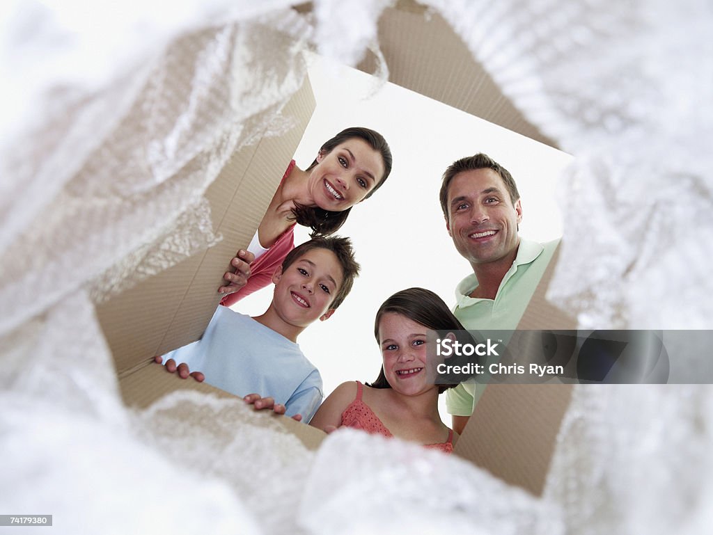 Homme et femme avec petit garçon et fille regardant dans Boîte en carton - Photo de Boîte en carton libre de droits