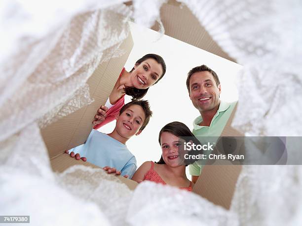 Photo libre de droit de Homme Et Femme Avec Petit Garçon Et Fille Regardant Dans Boîte En Carton banque d'images et plus d'images libres de droit de Boîte en carton